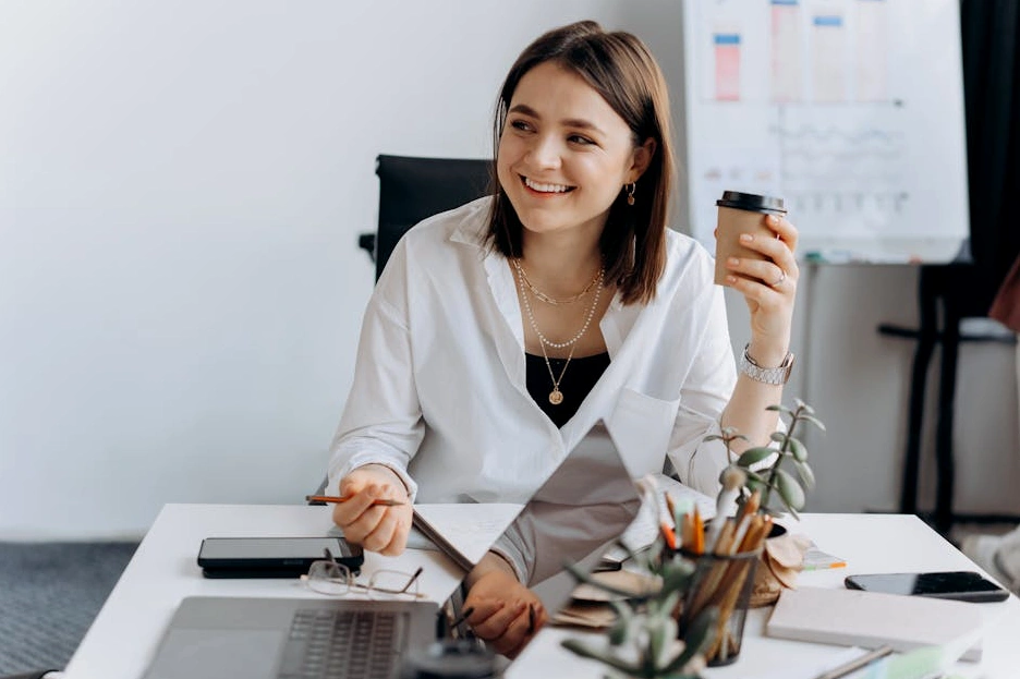 Elinde bir fincan kahve ile gelinlik modellerini inceleyen mutlu bir kadın